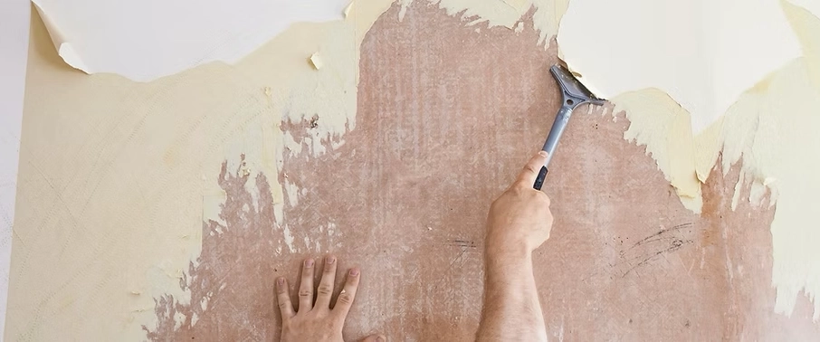 Neu's hands removing wallpaper from a wall